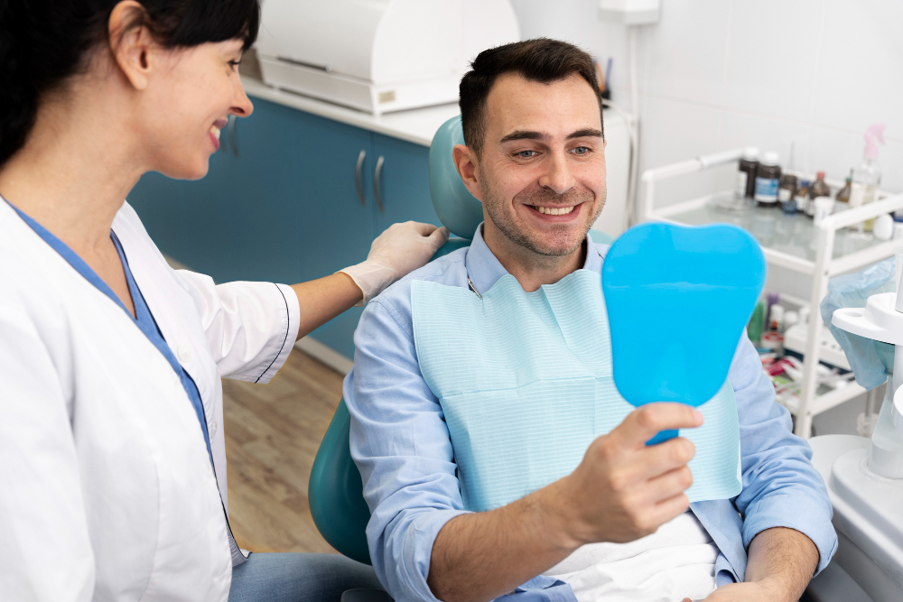 A happy client smiles as he looks in a mirror while a dentist watches