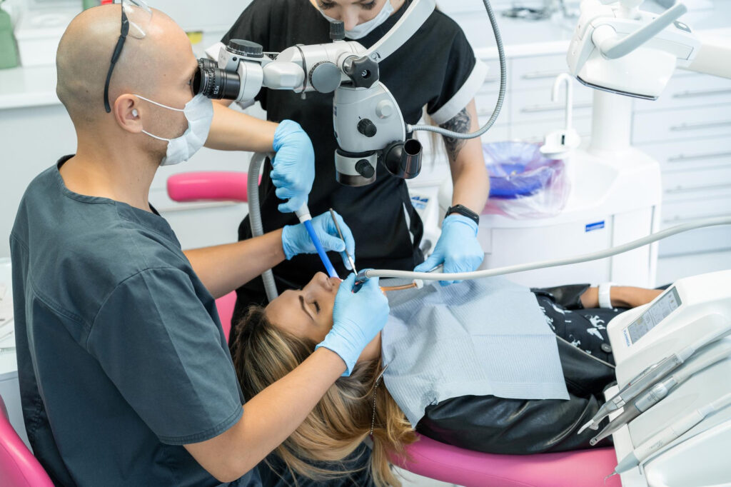 A dentist performing surgery on a patient while a technician helps.