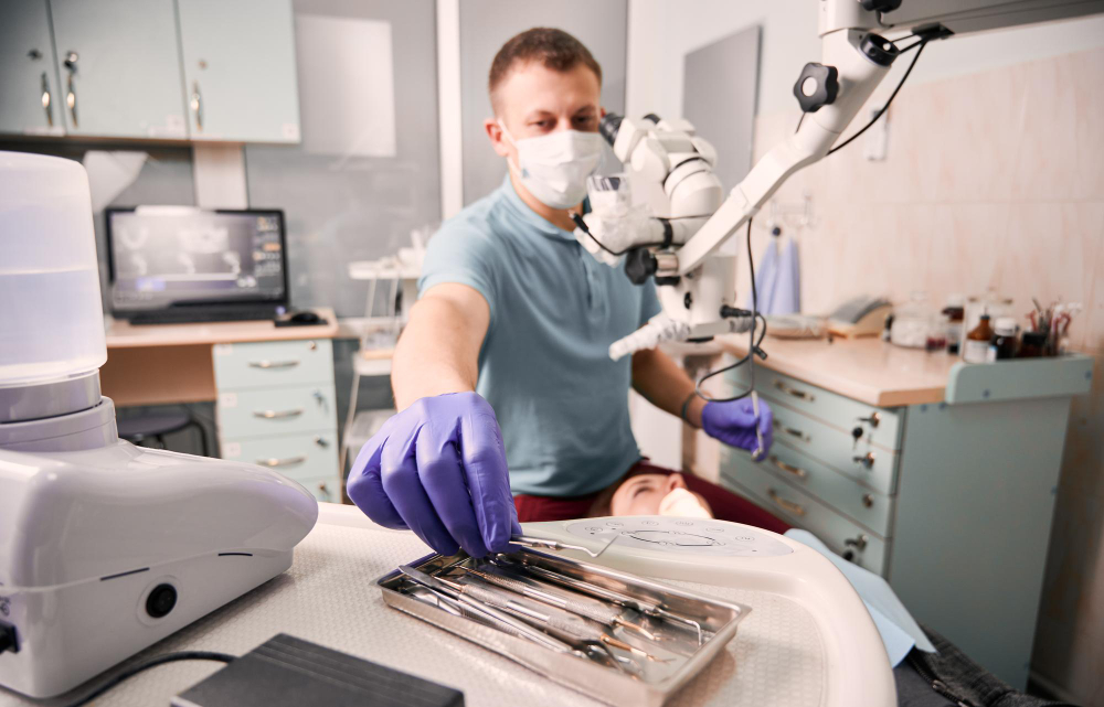A dentist reaching for dental instruments next to a robotic mechanism in front of him.