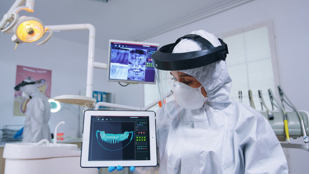 A Dental specialist in front of a monitor that shows a dental X-Ray