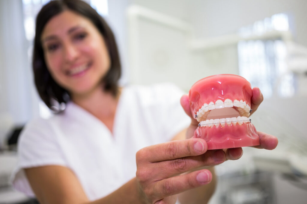 A dentist holding a denture in the foreground