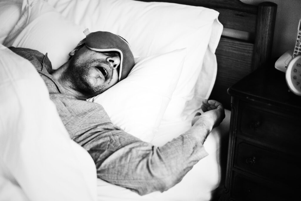 A man snoring with some eye shades in bed
