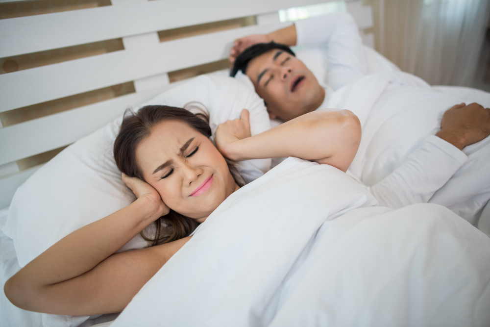 A wife in bed with her husband, trying to sleep with his snoring and struggling