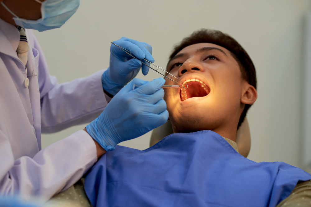 A young man on a dentist chair being inspected before a tooth extraction