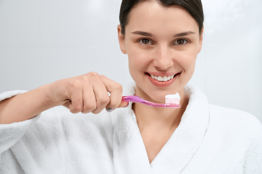 A young Woman holding a brush with toothpaste and smiling